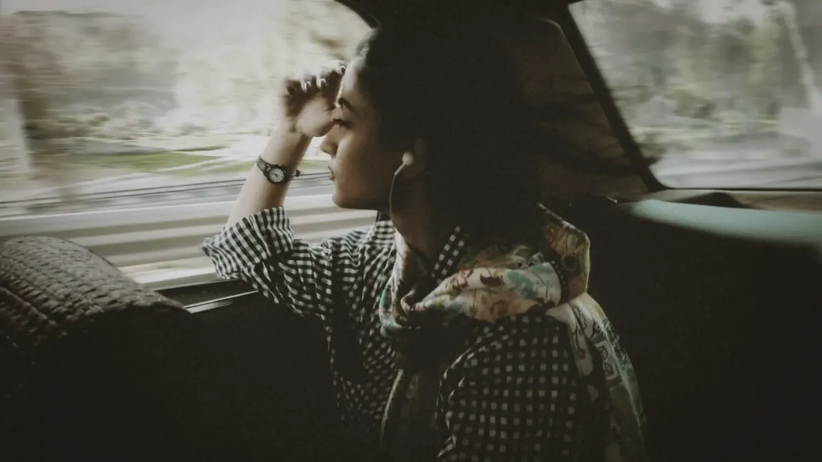 A dog sitting in the backseat of a car, looking tense while gazing out the window