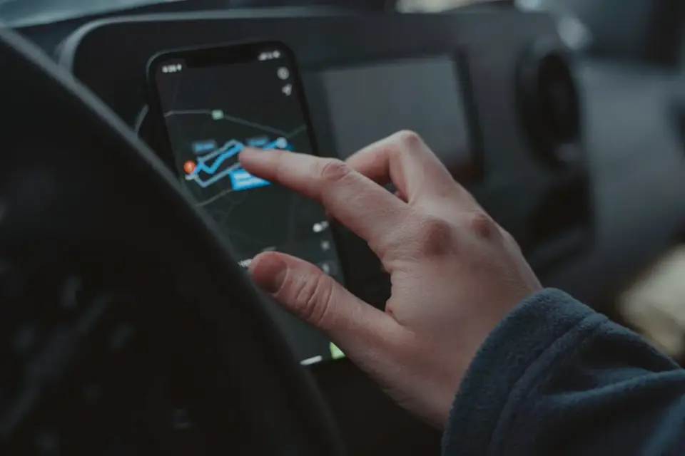 A person checking a dog GPS tracking app on their phone while their dog waits nearby