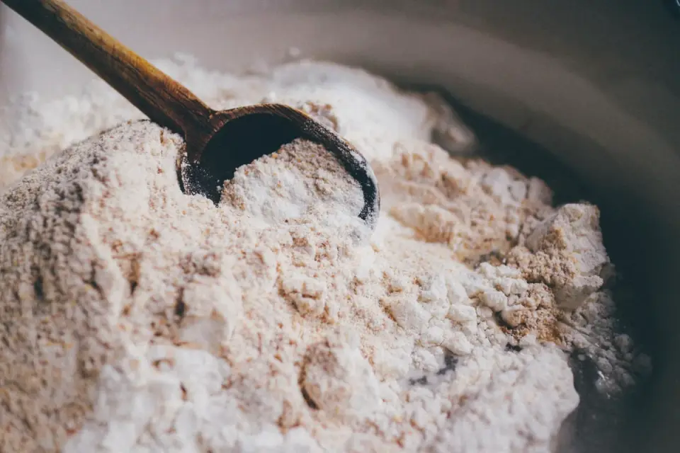 A scoop of dehydrated pumpkin powder being added to a bowl of dog food