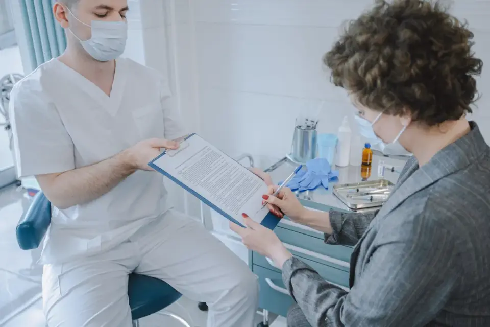 A veterinarian pointing to a bloodwork printout while a dog owner looks on