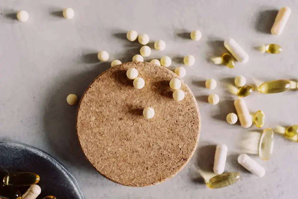 Fish oil softgel capsules next to a wooden spoon of flaxseed